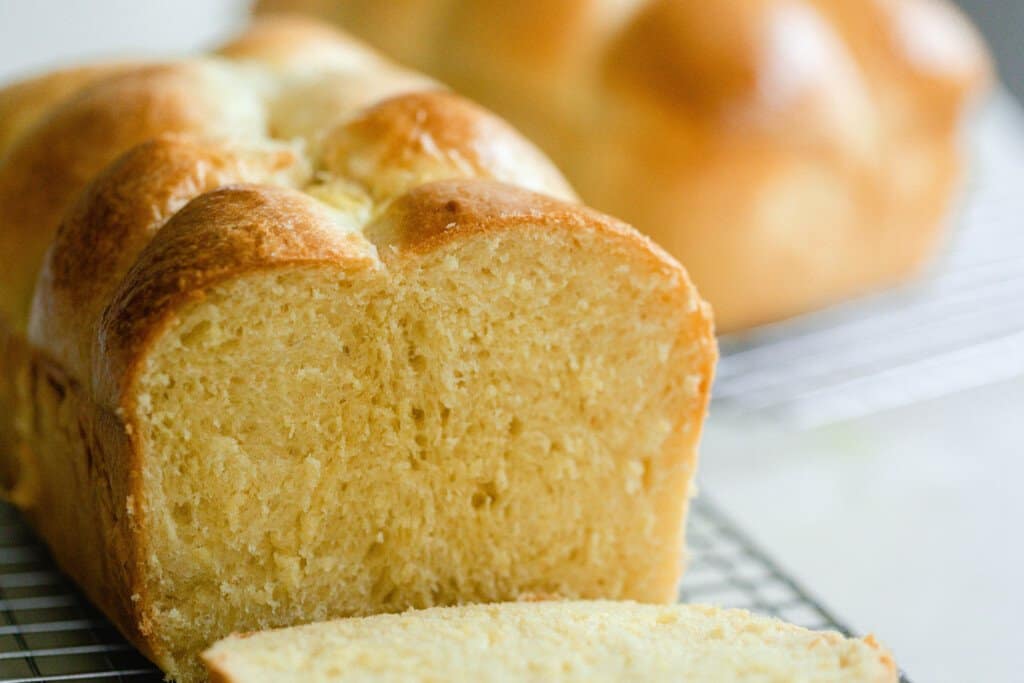 sourdough brioche sliced on a wire rack with another loaf in the background