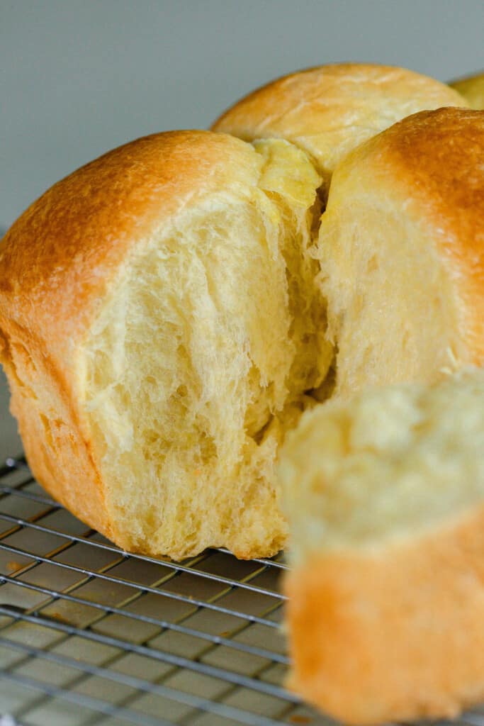 sourdough brioche with a piece broken off revealing light and fluffy bread.