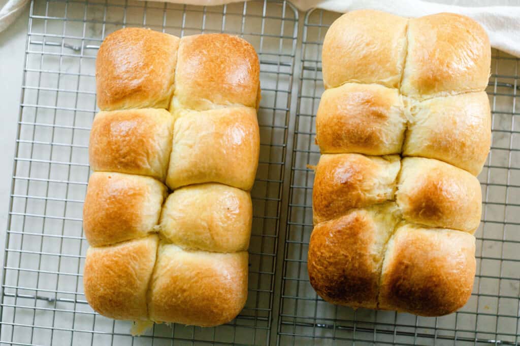 overhead picture of two loaves of sourdough brioche on a wire rack on a white countertop