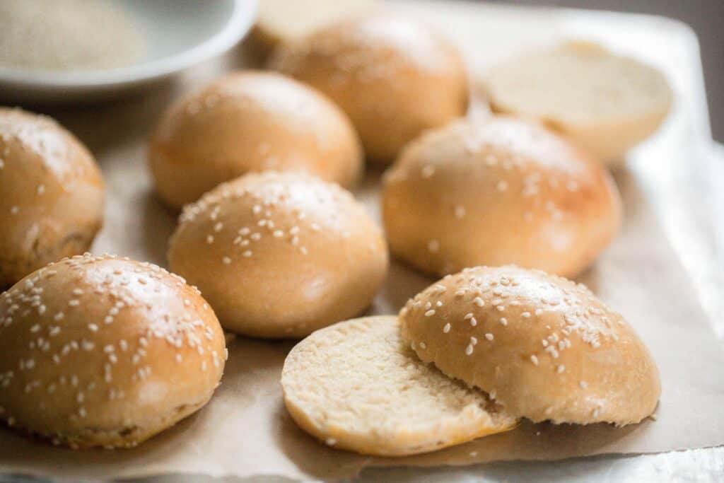 sourdough hamburger buns topped with sesame seeds on parchment paper