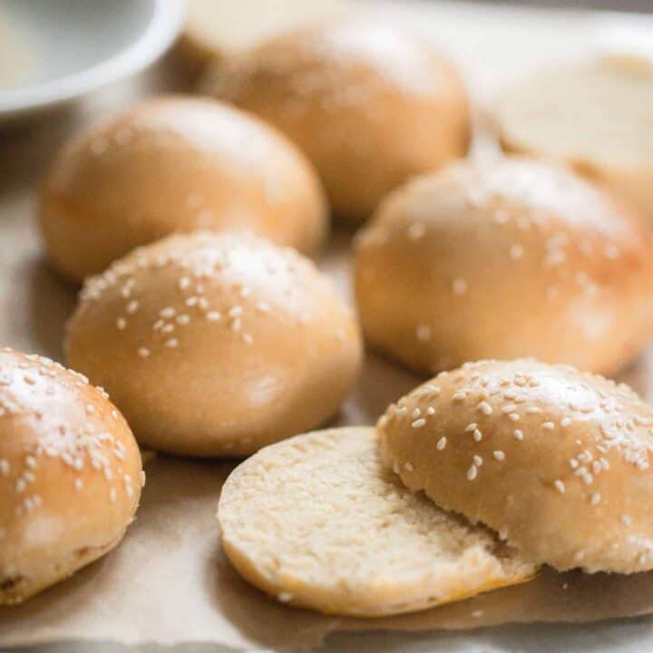 sourdough hamburger buns topped with sesame seeds on parchment paper