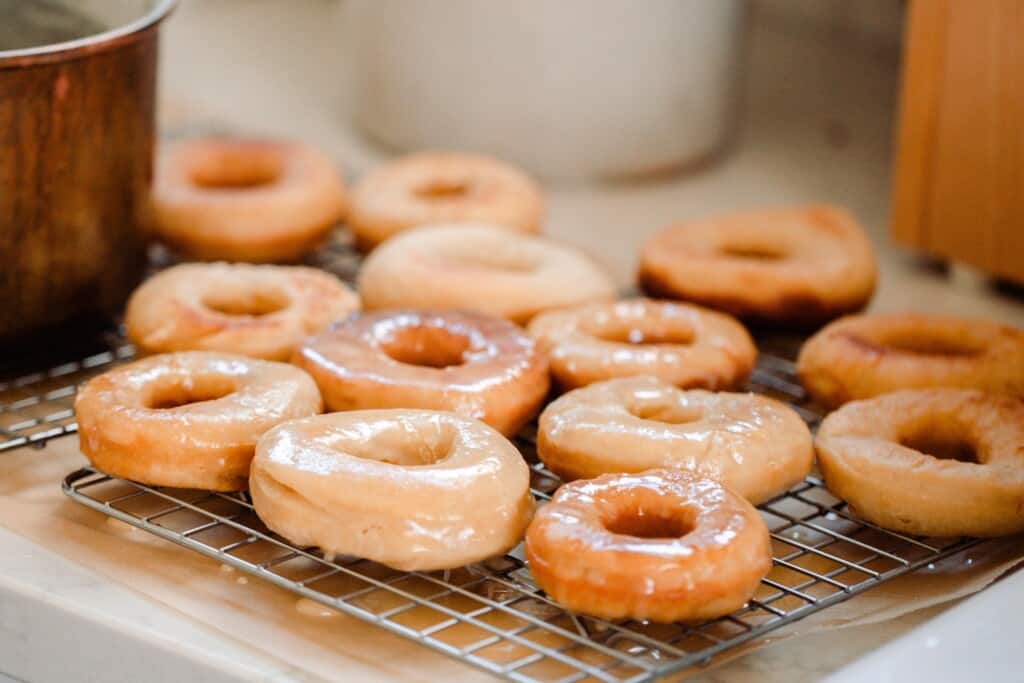 sourdough donuts with a vanilla glaze on a wire rack over parchment paper