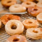 glazed sourdough donuts drying on a wire rack over parchment paper.