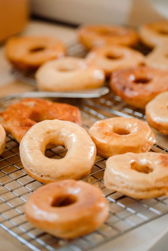 glazed sourdough donuts drying on a wire rack over parchment paper.