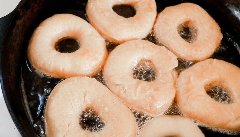 frying sourdough donuts in a cast iron skillet with coconut oil