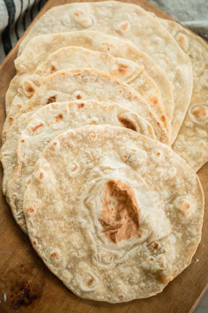 sourdough tortillas spread on on top of a wood cutting board