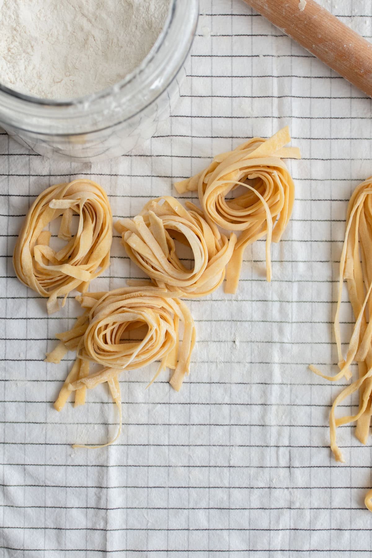 Rolls of pasta on a striped tea towel.