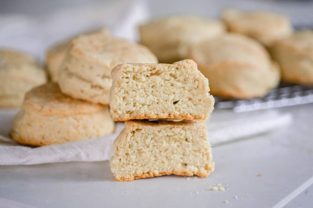 sourdough biscuit cut in half and stacked on top of each other with more biscuits in the background 