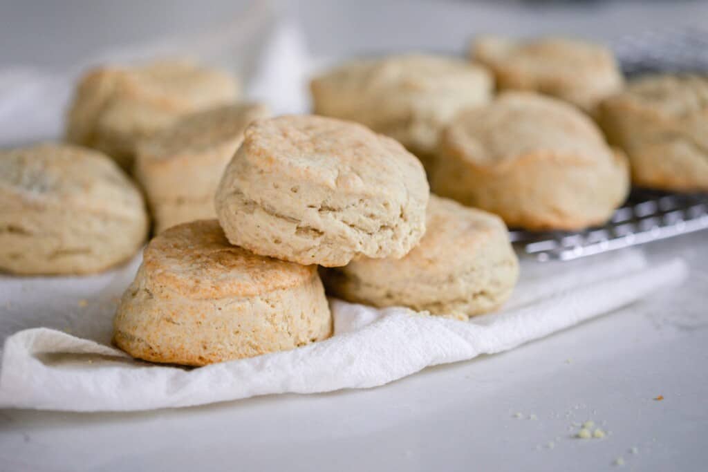 sourdough biscuits stacked on top of each other on a cream colored tea towel on a white countertop
