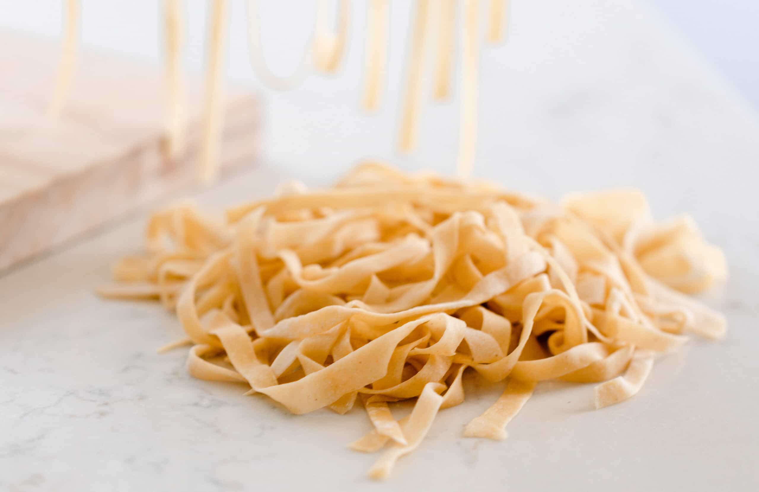 sourdough pasta noodles in a pile on a white and gray quartz countertop