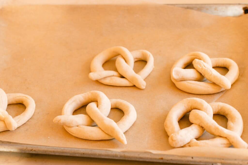 sourdough pretzel dough placed on a parchment lined baking sheet ready for the oven