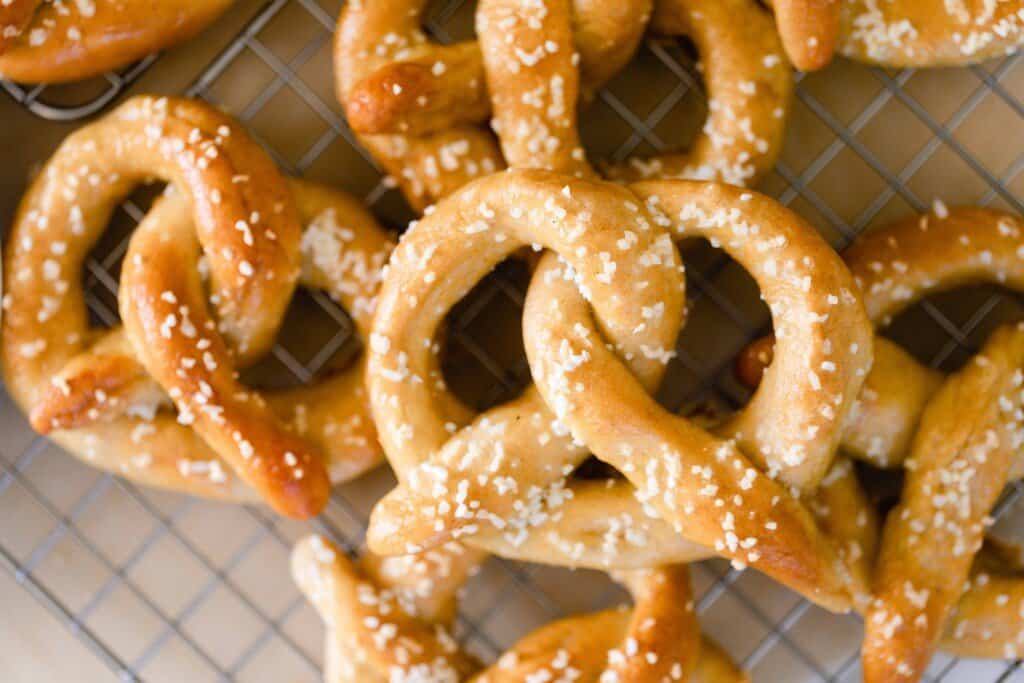 sourdough pretzels with salt stacked on top of each other on a wire rack