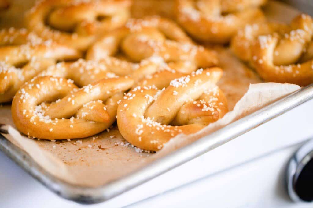 side view of a baking sheet lined with parchment paper with lots of homemade pretzels on the baking sheet
