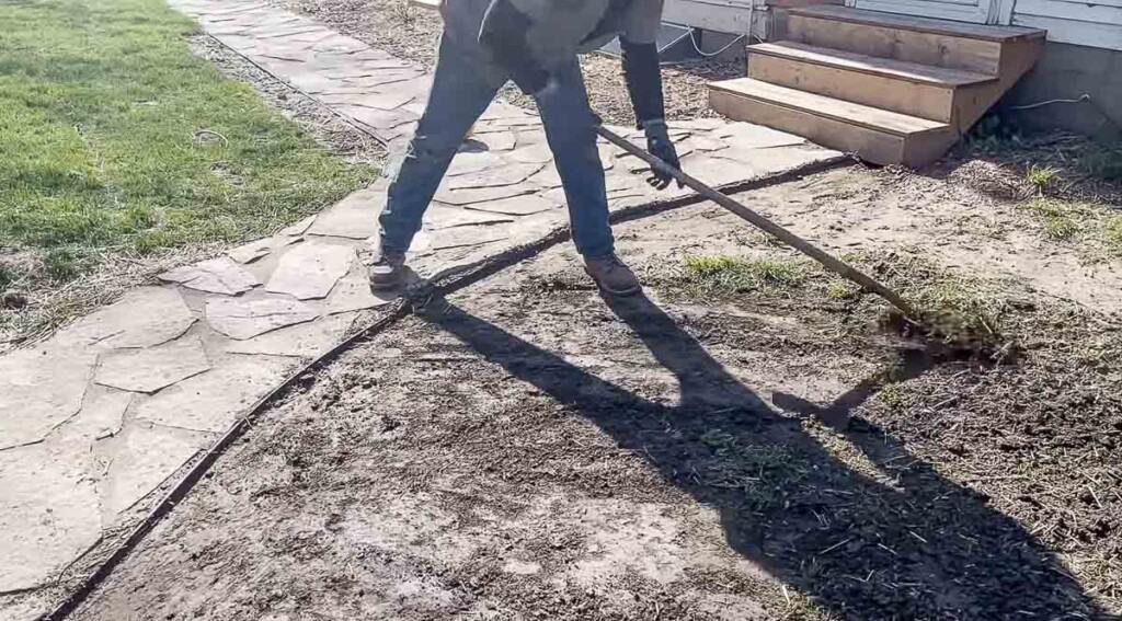 man scraping grass off of dirt with a shovel