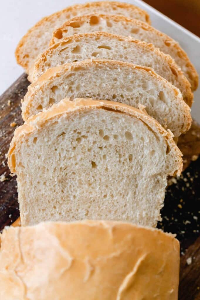 a loaf of sourdough bread sliced on a wood cutting board 