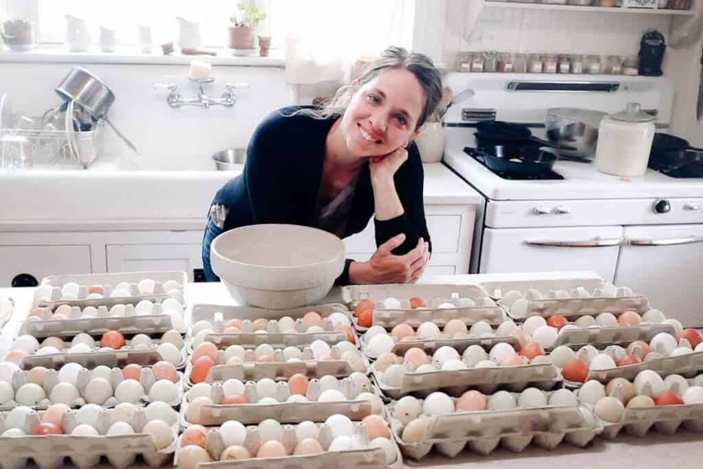 a women in a black shirt standing behind a countertop full of farm fresh eggs in cartons