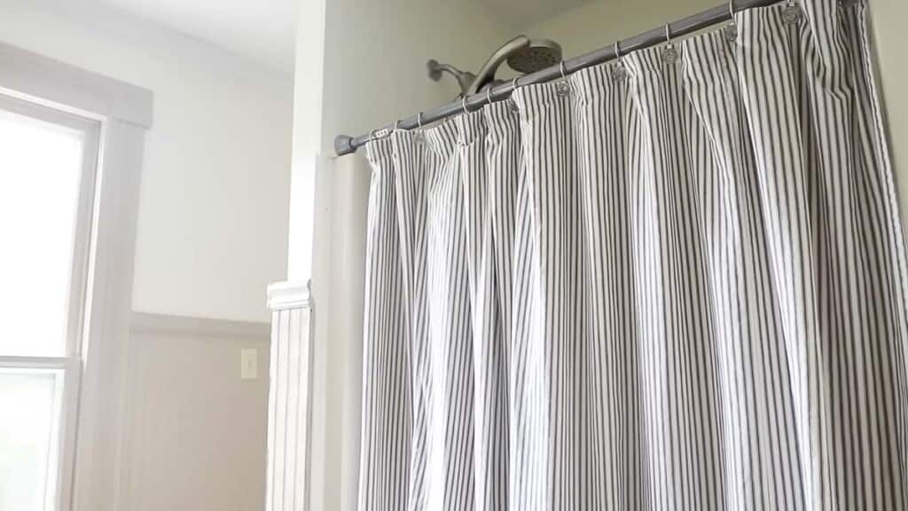 ticking stripe shower curtain hanging on a shower rod