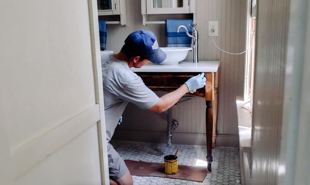 man staining a custom vanity with a marble top and bowls for sinks