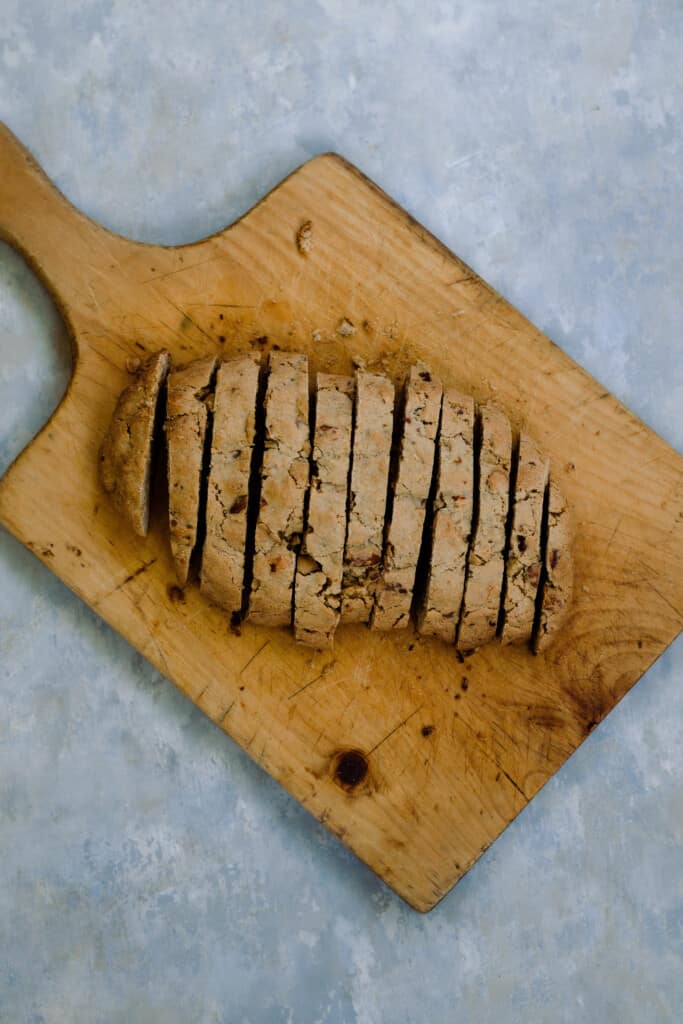 sourdough biscotti long sliced into thin cookies on a wooden cutting board on a gray countertop