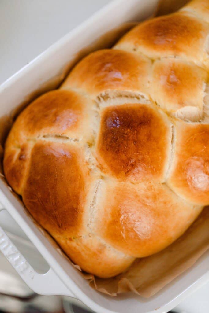 sourdough challah in a white baking dish on a white countertop