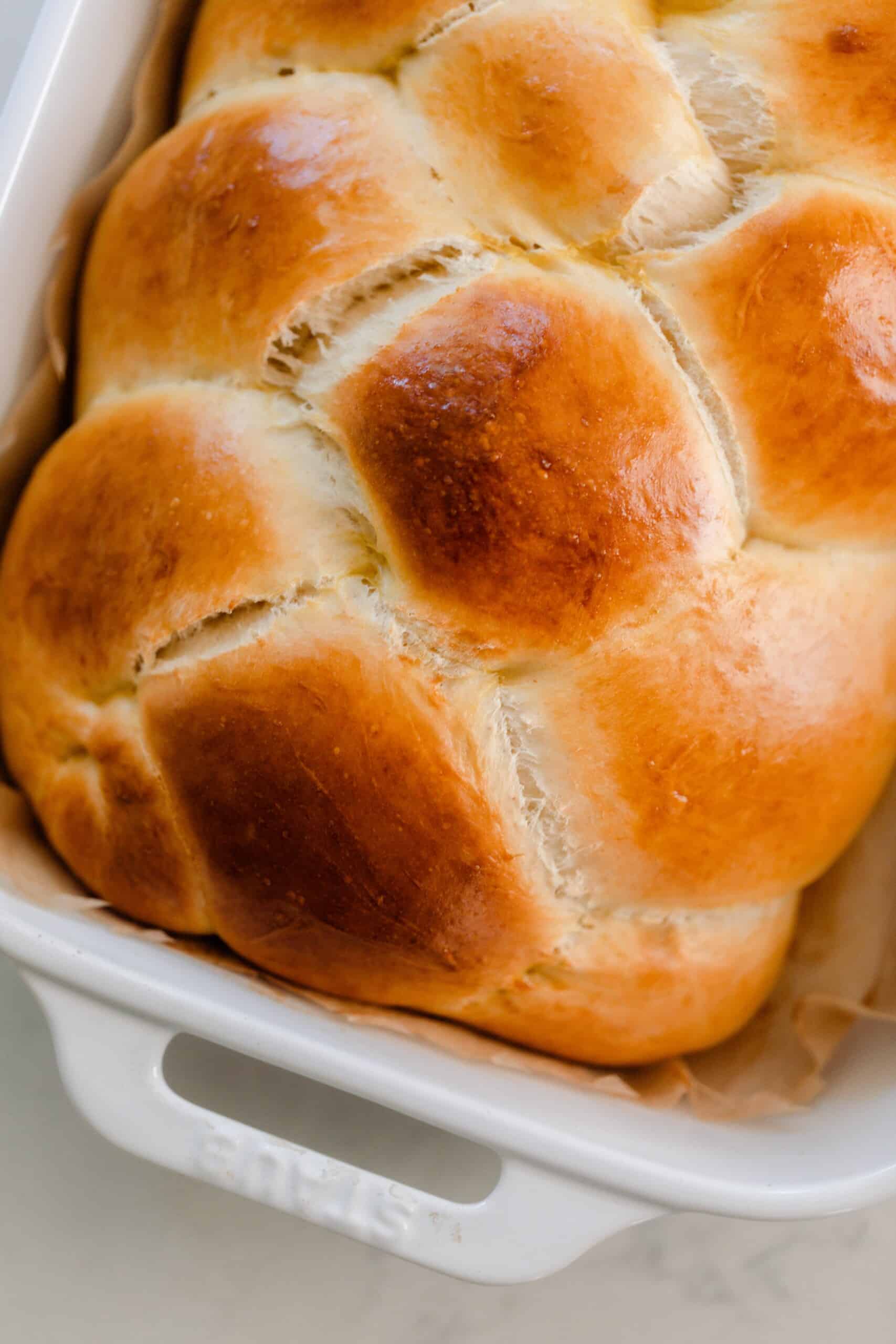 close up overhead photo of sourdough challah in a white baking dish