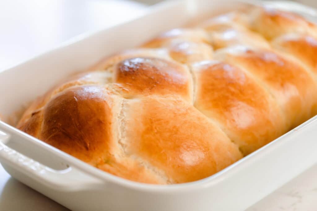 close up picture of sourdough challah in a white stoneware bakeware