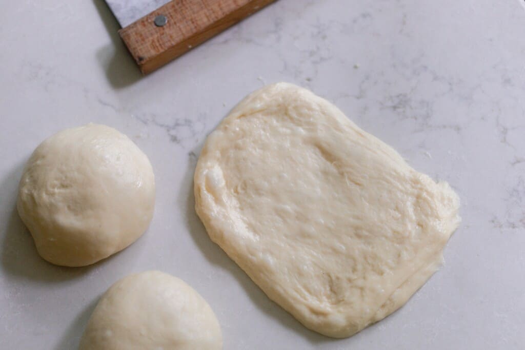 sourdough dough balls being rolled out into small rectangles