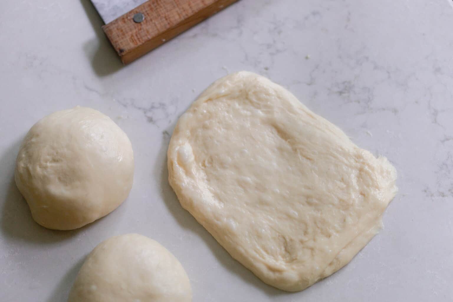 sourdough dough balls being rolled out into small rectangles