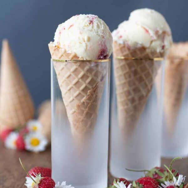 Two ice cream cones with one scoop of ice cream in frosted glasses.