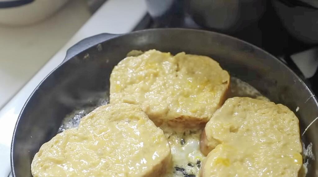 three slices of custard soaked brioche in a cast iron skillet