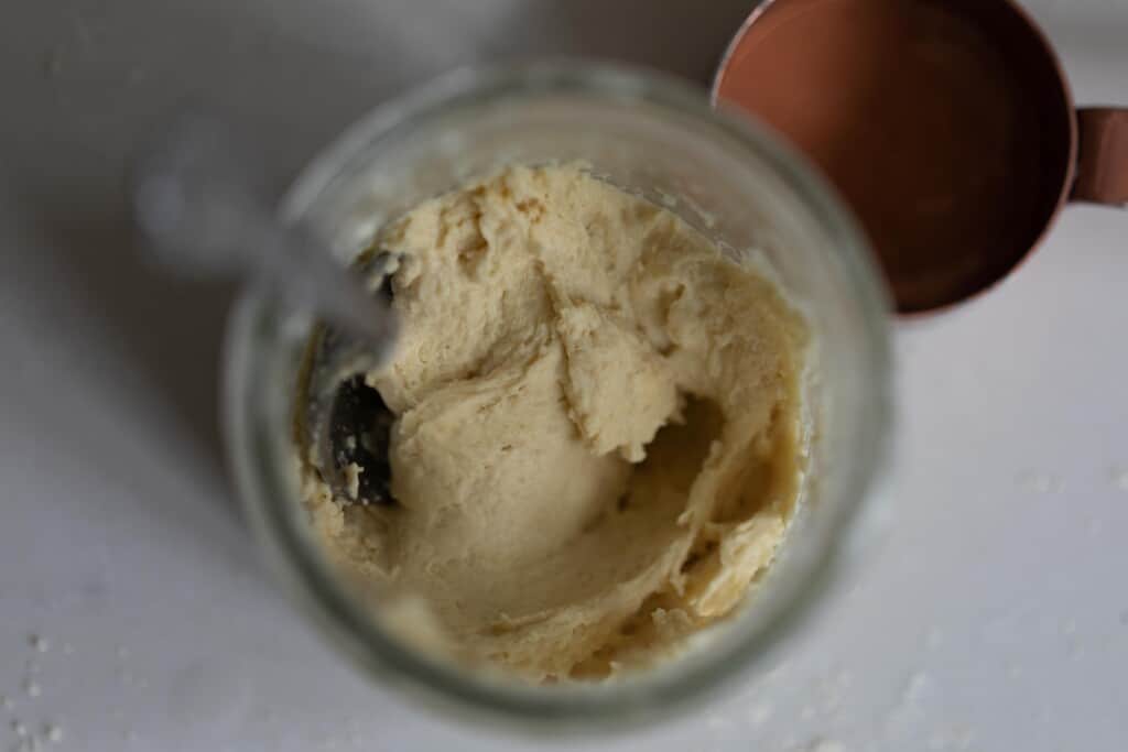 einkorn flour and water mixed together in a jar on a white countertop