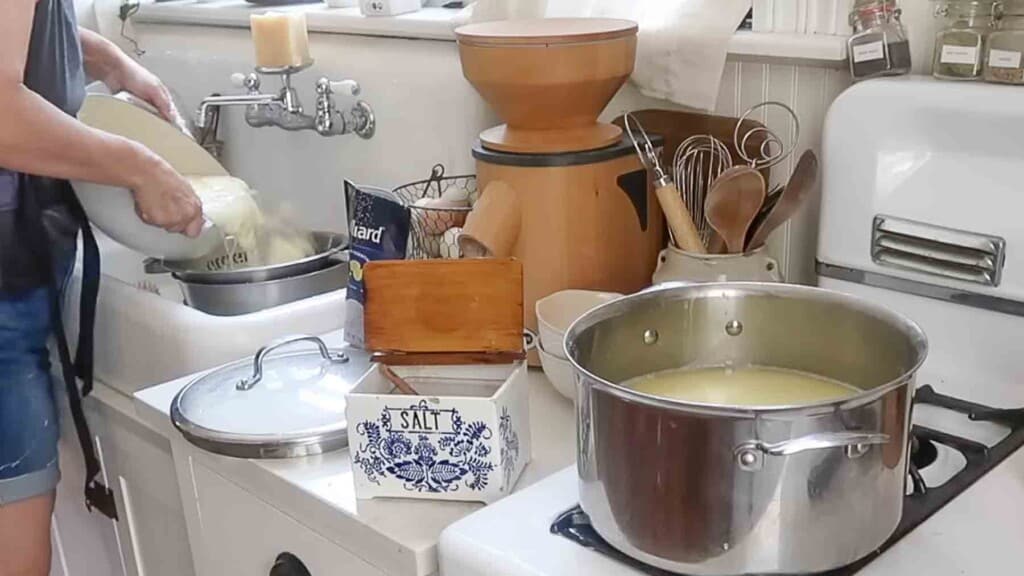 woman pouring a pot of curds and whey through a colander