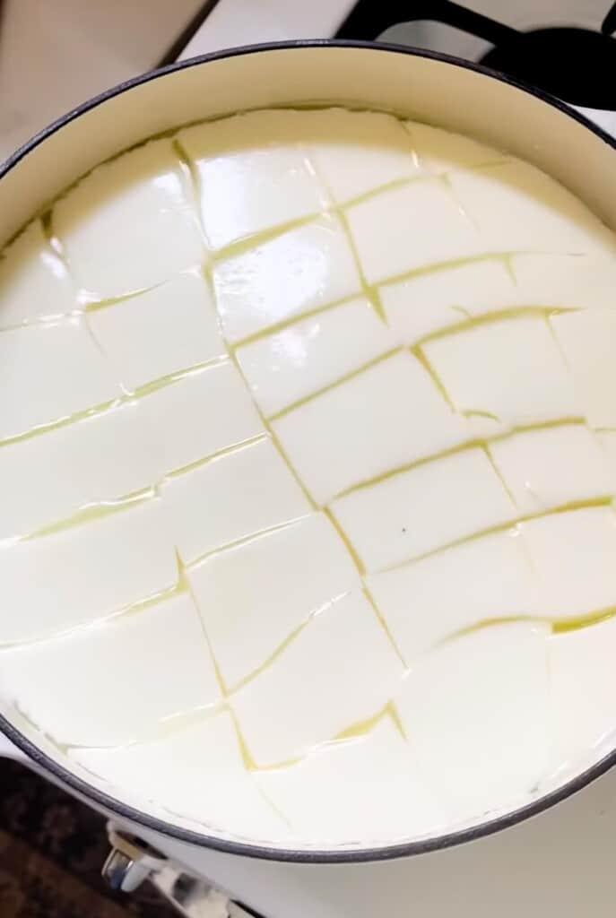 curds cut into a grid like pattern in a white dutch oven