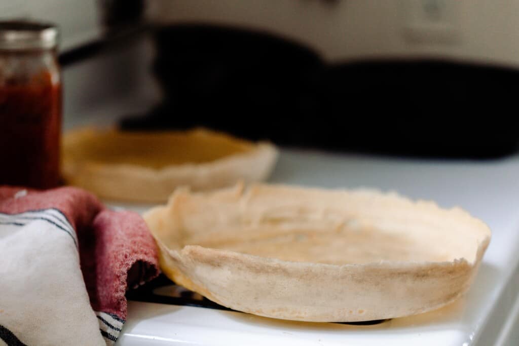 sourdough discard pizza crust on an antique stove with a red and cream colored towel to the left