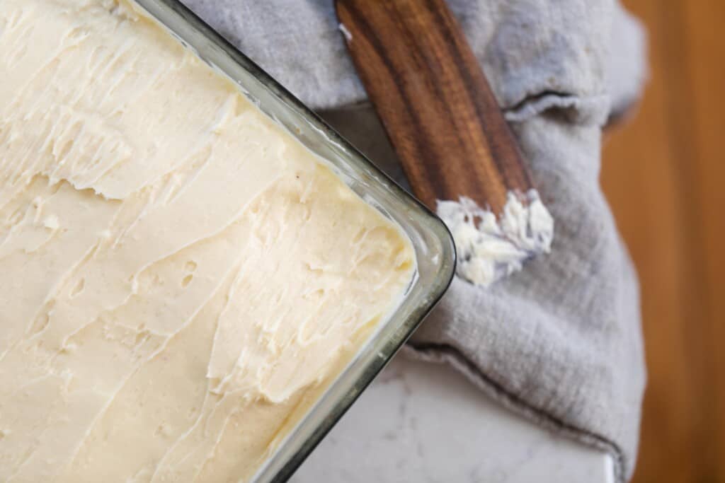 sourdough vanilla cake with buttercream frosting in a glass baking dish on a gray linen napkin