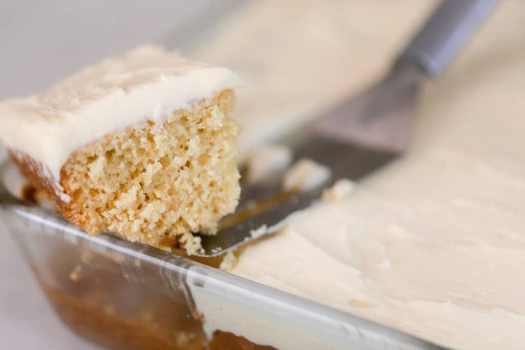 A spatula taking out a square piece of sourdough cake from a baking dish