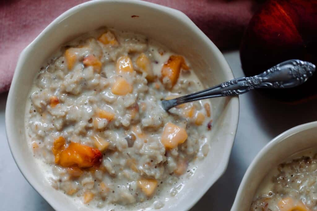 overhead photo of oatmeal and peaches in a white bowl