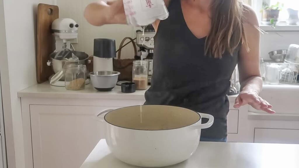 woman wearing a black shirt pouring milk into a dutch oven