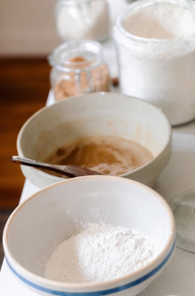 a bowl of dry ingredient and another bowl of wet ingredients on a white countertop