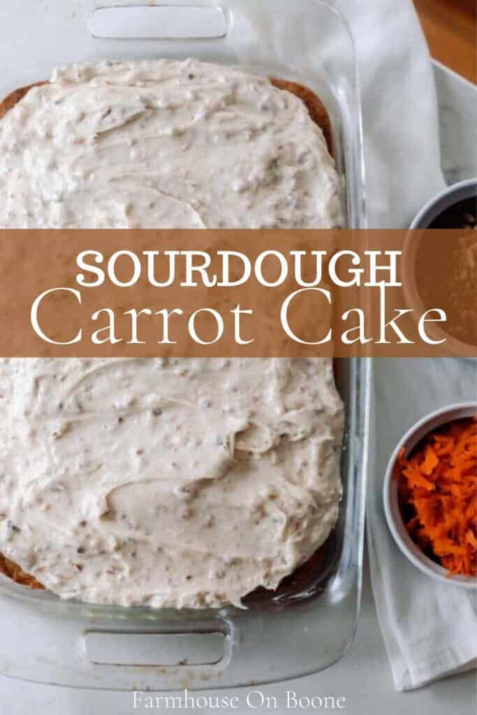 overhead photo of sourdough carrot cake topped with cream cheese pecan frosting on a white countertop with a napkin and jars of shredded carrots and chopped pecans to the right