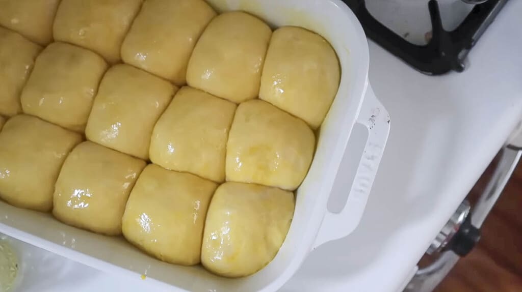 rolls topped with an egg wash in a white baking dish on a white stove