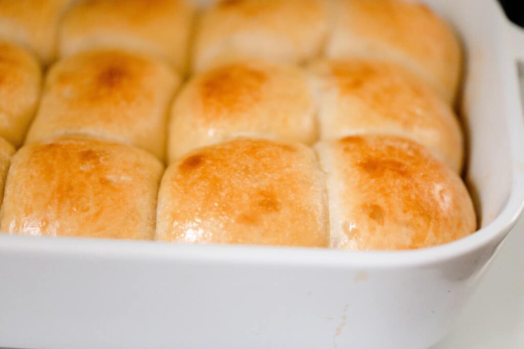close up of freshly baked sourdough sweet rolls in a white ceramic baking dish