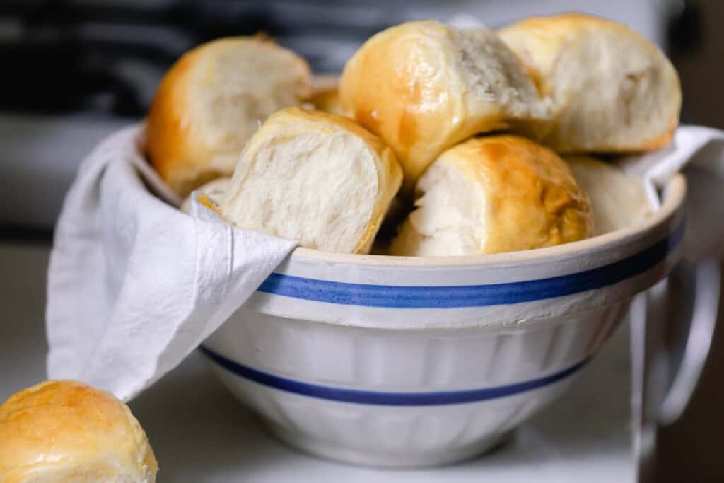 bowl of sourdough sweet rolls on a white countertop with a vintage stove in the background