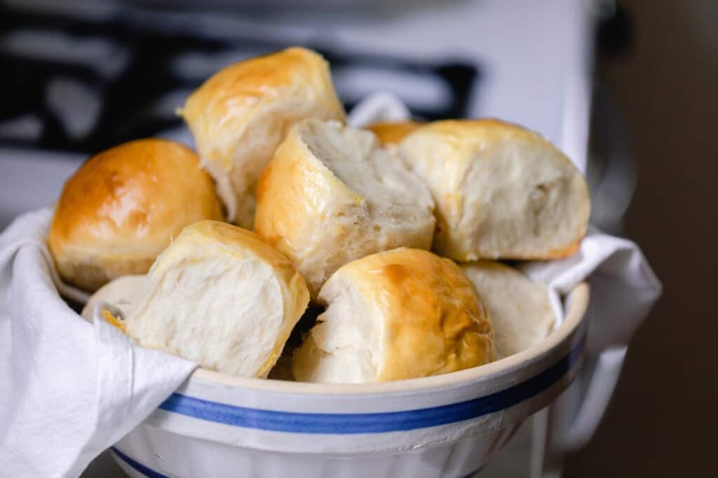 side view of a bowl full of Hawaiian sweet rolls with a vintage stove in the background