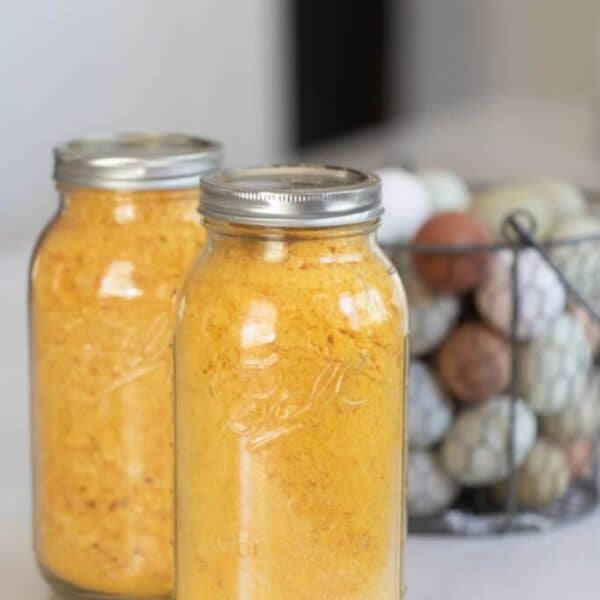 Two large mason jars of freeze dried eggs with a basket of fresh eggs in the background.
