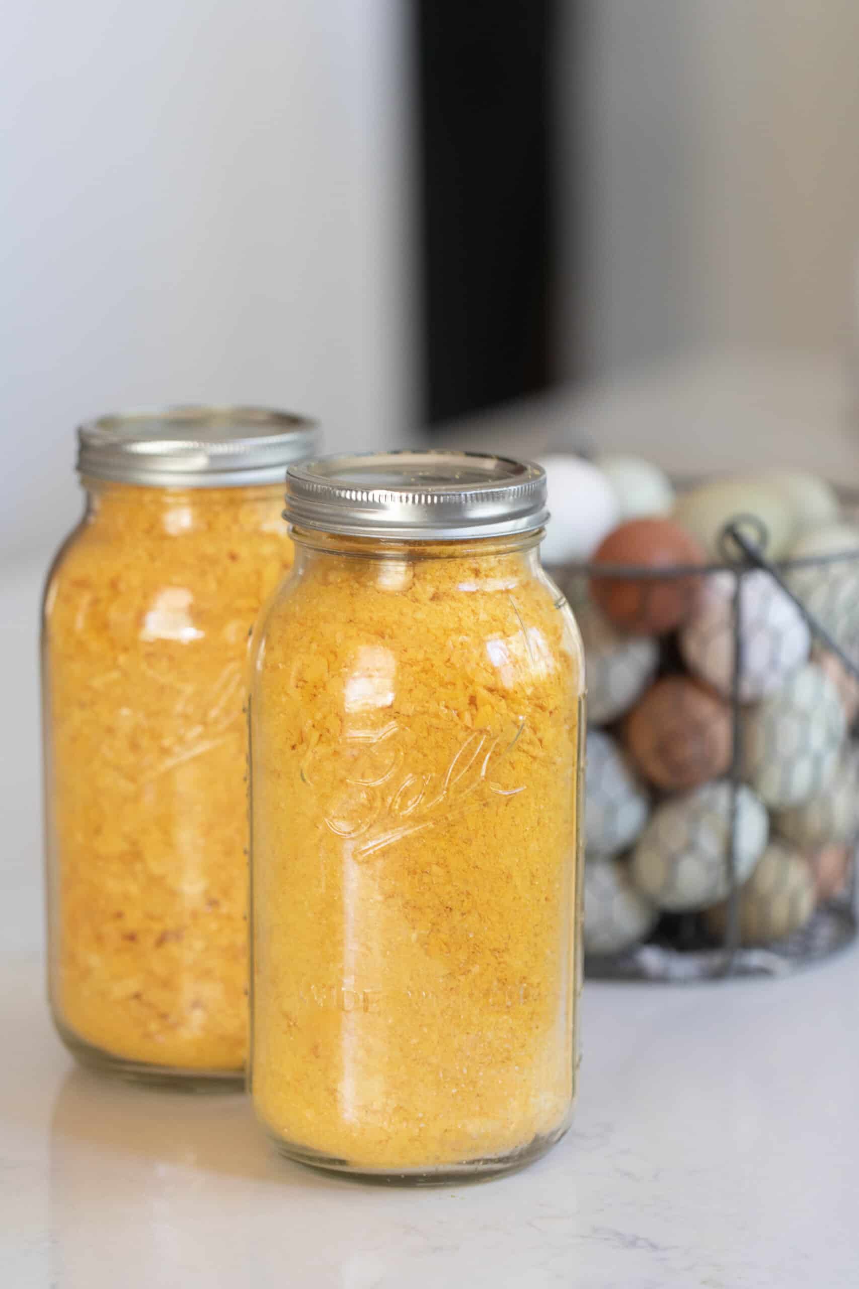 two jars of freeze dried eggs on a countertop with a basket full of eggs behind it