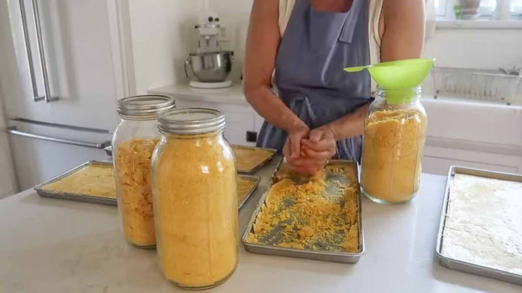 woman placing freeze dried peach preserves into 1/2 gallon mason jars.