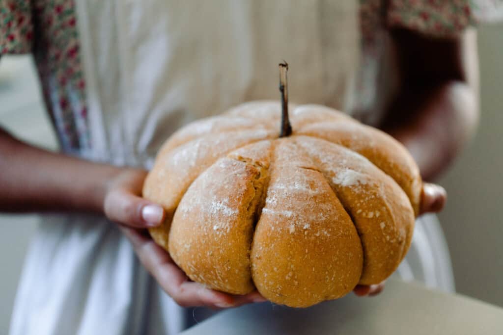 girl holding a pumpkin shaped sourdough loaf 