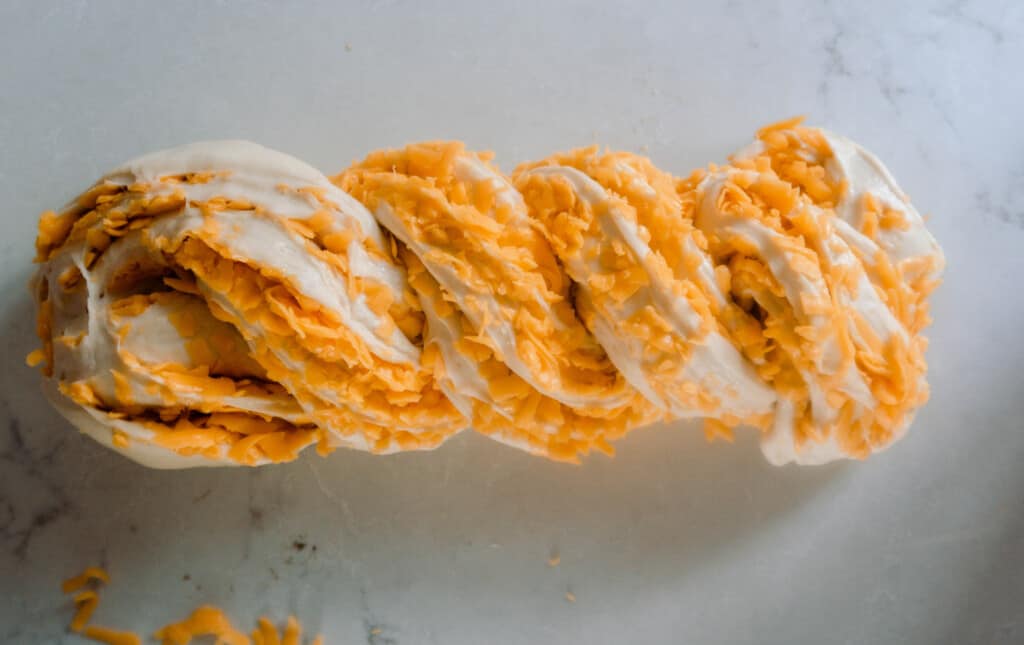 sourdough cheese bread dough twisted together on a white countertop