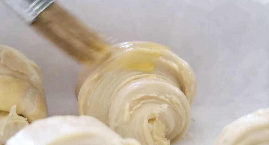 egg wash being brushed on sourdough croissants before baking